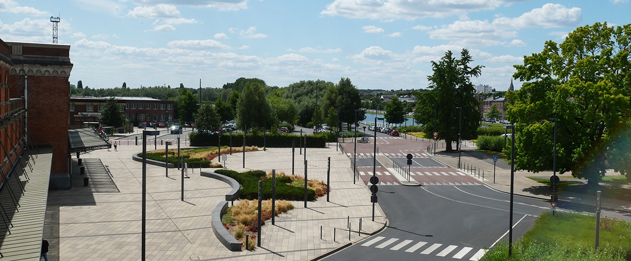 Ambiance urbaine devant la gare de Saint-Quentin, entre mobilité et shopping local